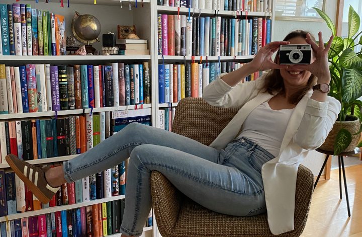 Carina Simone Weber mit Kamera vor Bücherwand